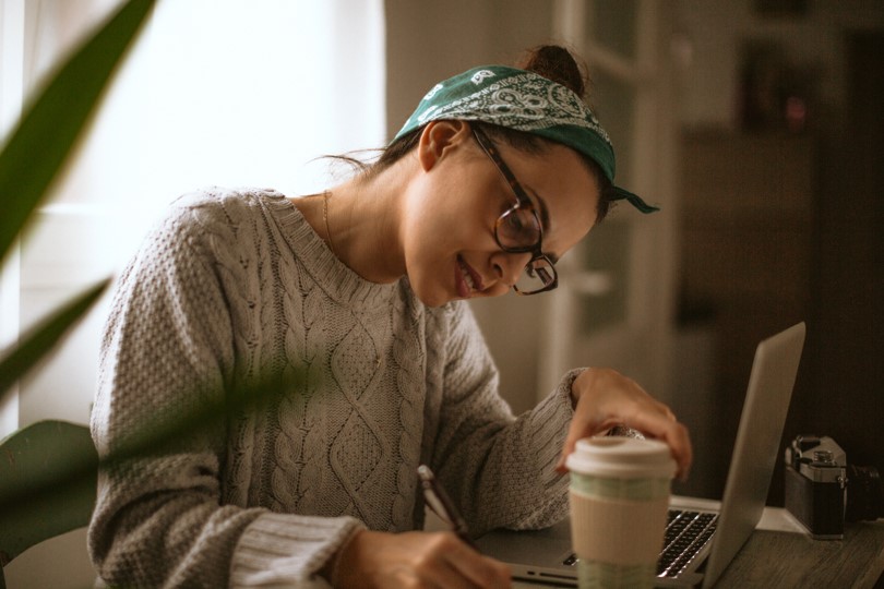 A woman reading online banking tips from New Omni Bank at home with her laptop.