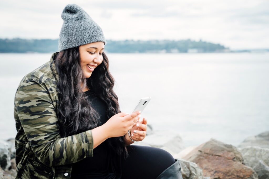 A woman reviewing social media settings on a cellphone, ensuring online privacy and security