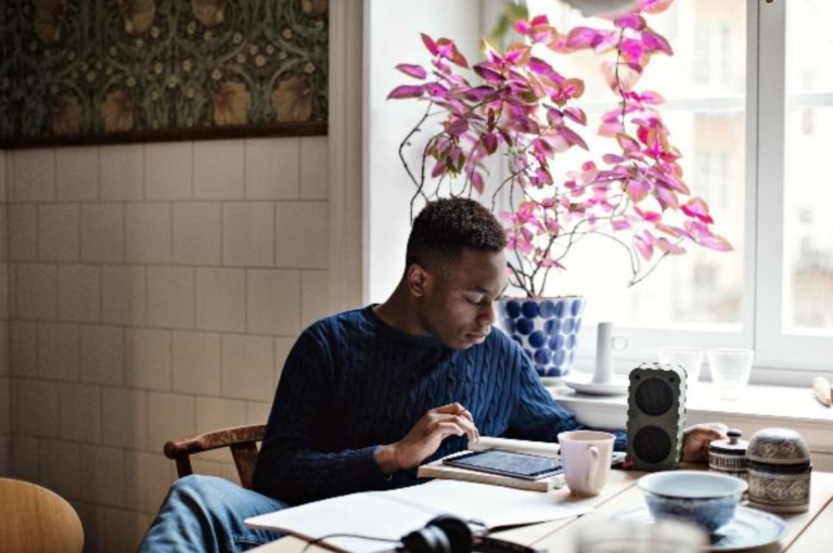 A man using tablet at home, reviewing mobile device safety measures provided by New Omni Bank.