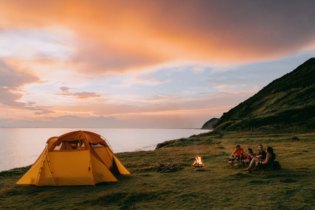 A family camping by the sea with dramatic sky at sunset.