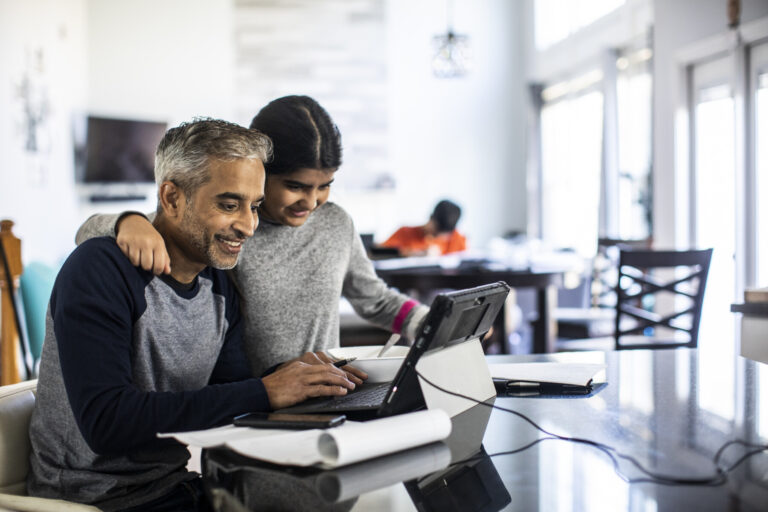 A father teaching his daughter about online security by referring to the guides from New Omni Bank.