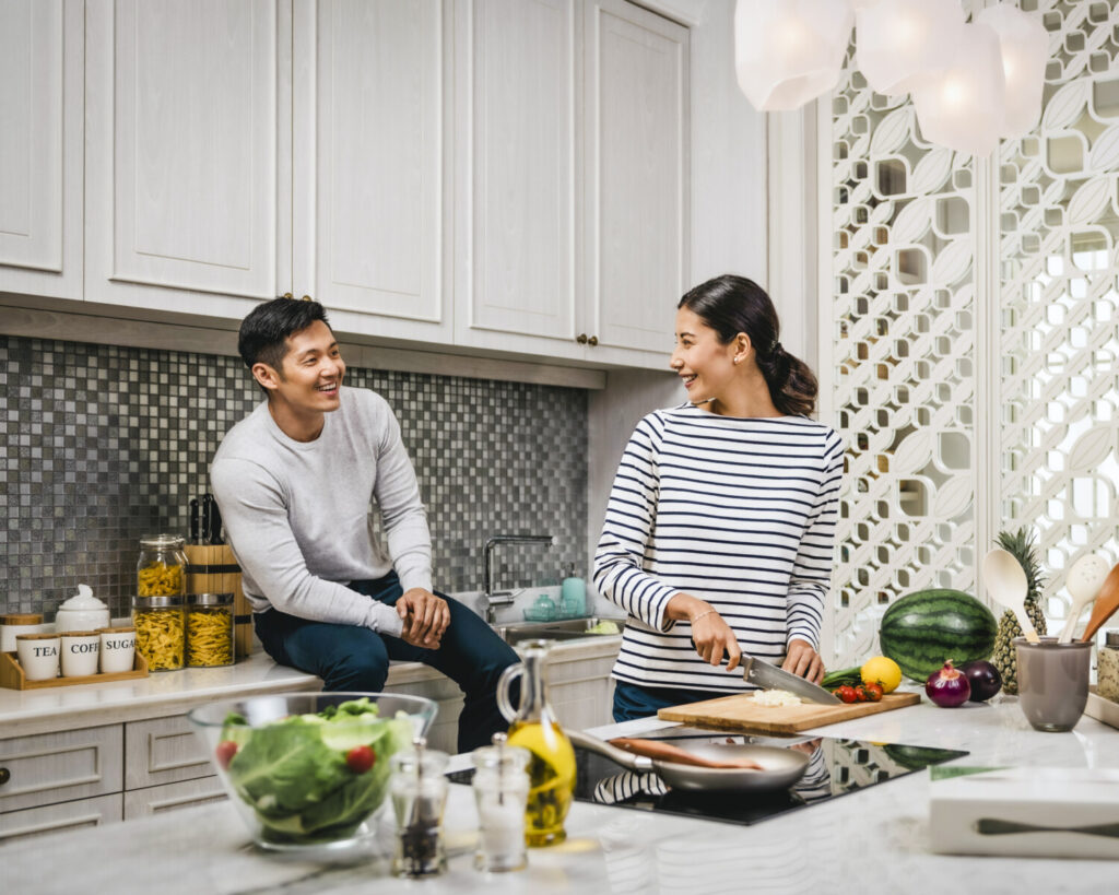 A young multiracial couple at their new home, cooking in the kitchen.