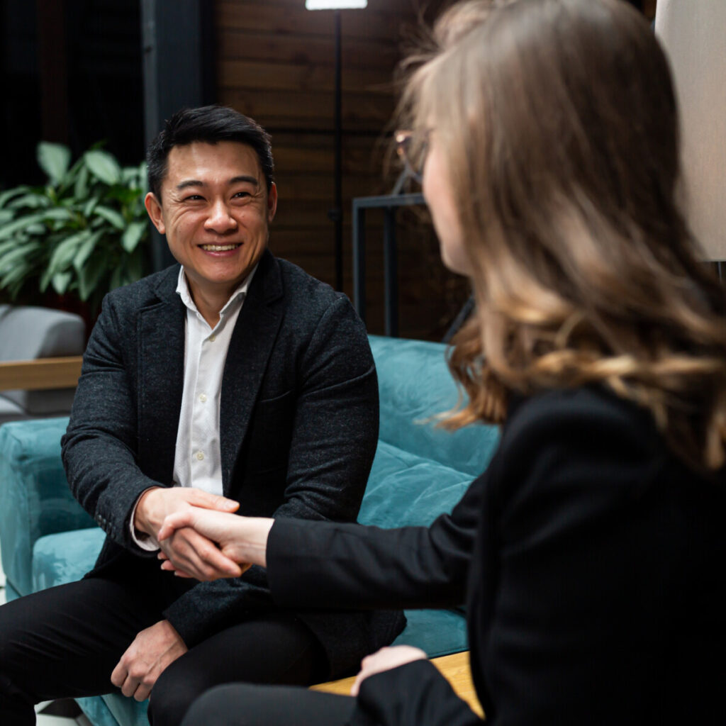 A man and a woman end a business meeting, shake hands, and rejoice in a successful deal.