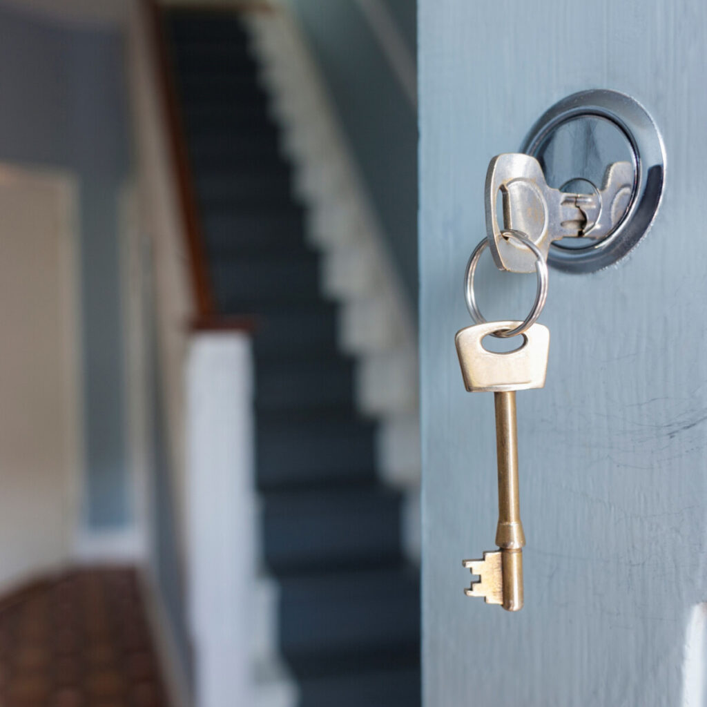 A key in the lock of an open door, symbolizing new home ownership opportunities valued by New Omni Bank.