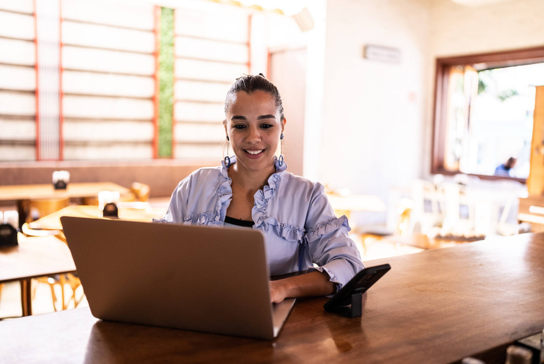 An adult woman using the laptop at a restaurant.