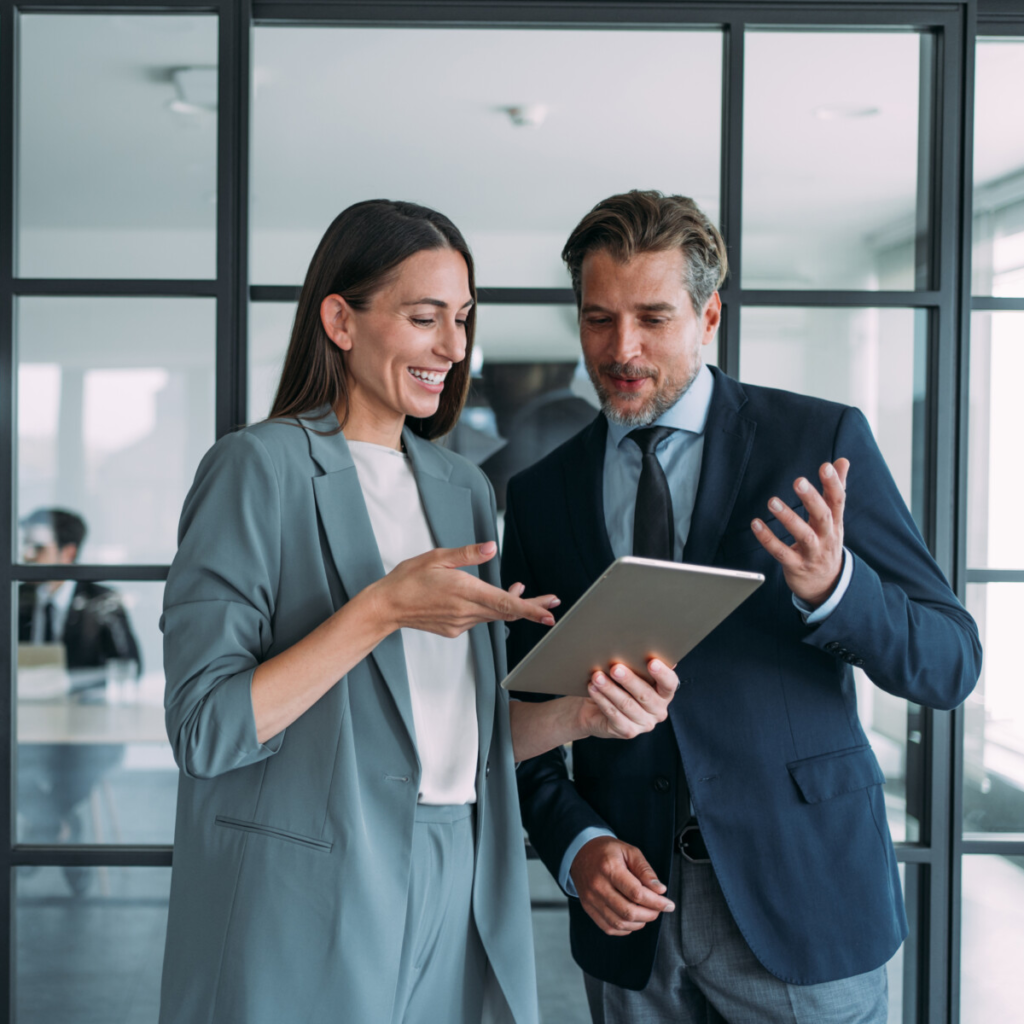 Two happy businesspeople happily reviewing their company finances with their tablet.