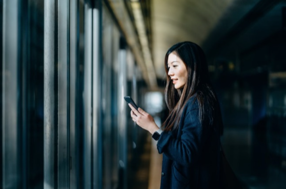 A woman holding smartphone on hand waiting for the metro.