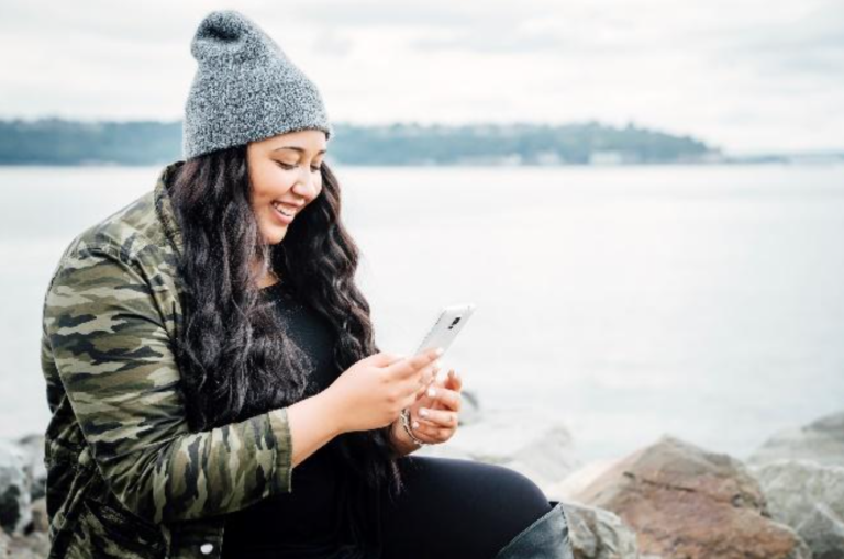 A woman reviewing social media settings on a cellphone, ensuring online privacy and security.