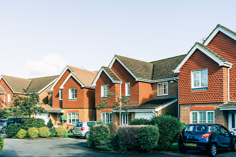 A row of brick houses with cars parked in front of them.