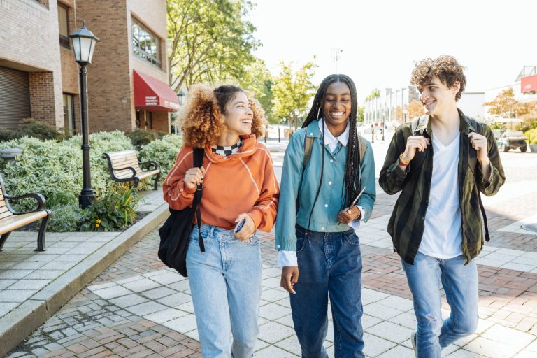 A diverse group of high school students laughing and talking together outdoors.