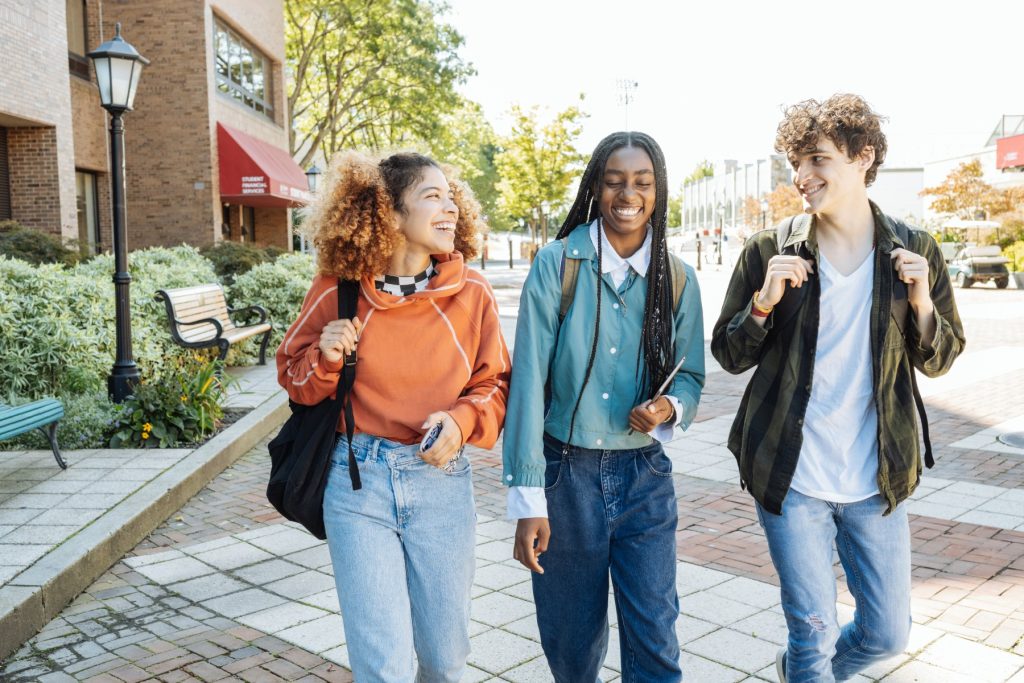 A diverse group of high school students laughing and talking together outdoors.