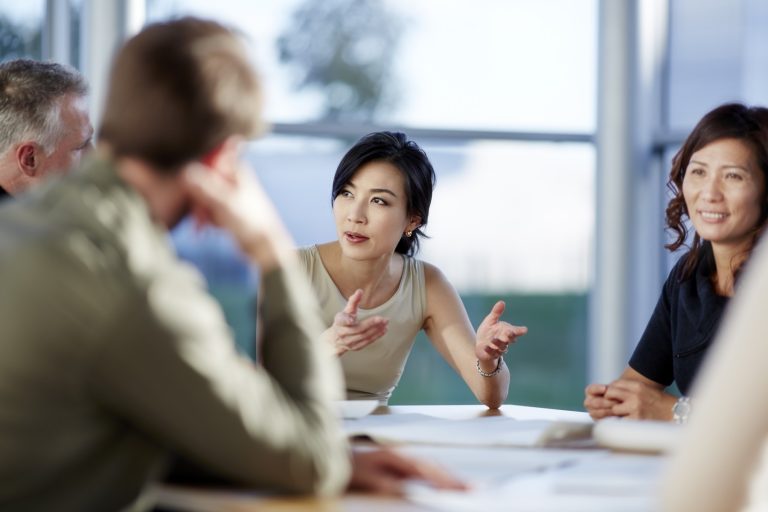 Business owner talking to her coworkers at a conference table, feeling confident and in control