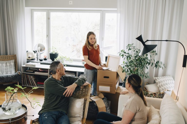 A young woman and her parents unpack boxes in their new home, symbolizing a mortgage secured with W-2s and tax returns