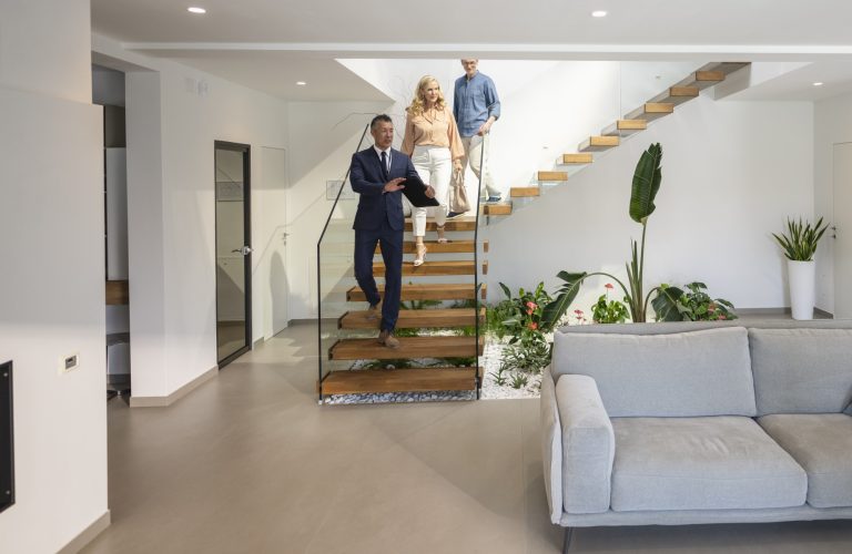 Real estate agent showing a luxury home to a couple — representing mortgage options for self-employed buyers