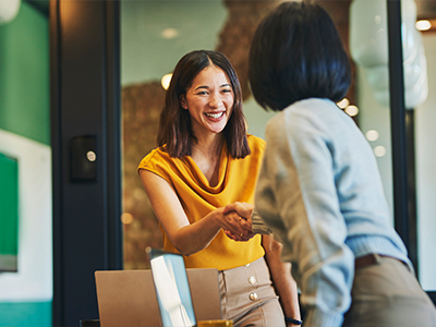 New Omni Bank banker shaking hands with client and smiling cheerfully in meeting room
