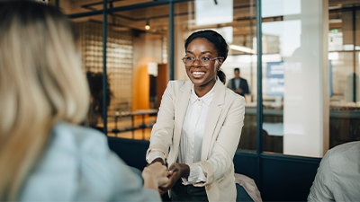 A smiling female client shaking hand with businesswoman after meeting at workplace