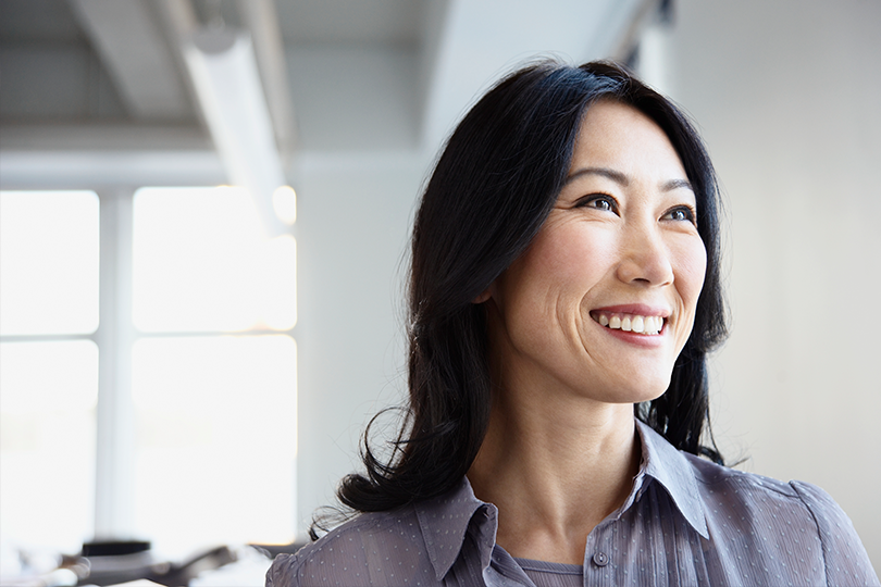 A confident business owner looking out the window from her office