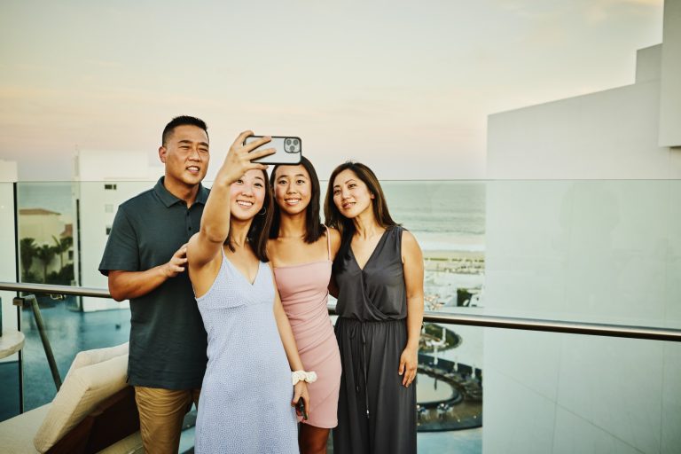 Smiling family taking a selfie at a rooftop restaurant in tropical resort during vacation