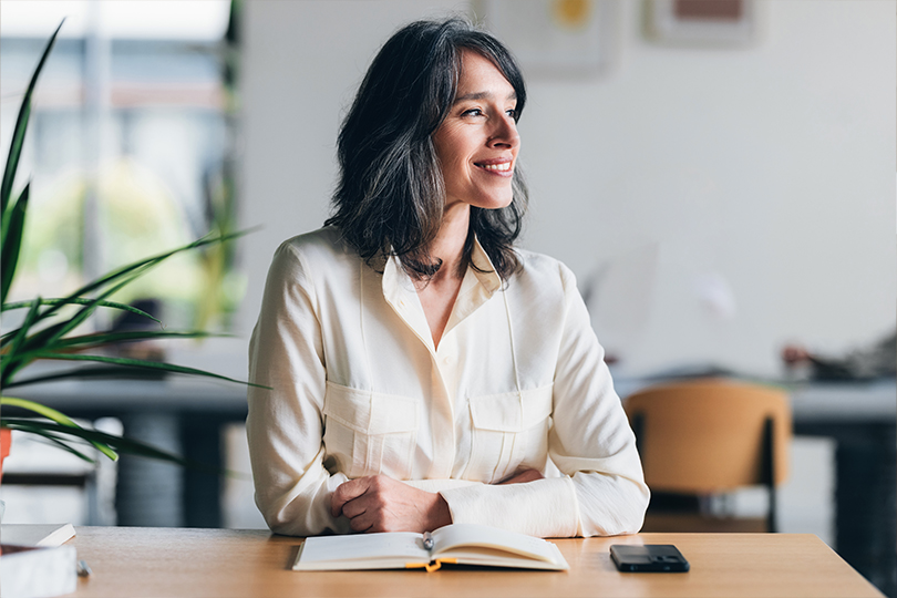 A confident woman smiling while sitting at a desk