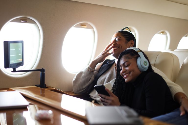 A mother and daughter laughing together while cuddling on a private jet