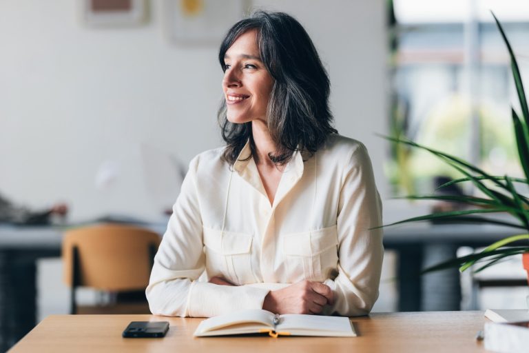 A confident woman smiling while sitting at a desk