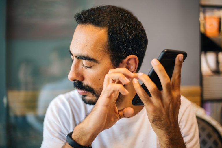 A man listening to his phone in a restaurant, looking worried