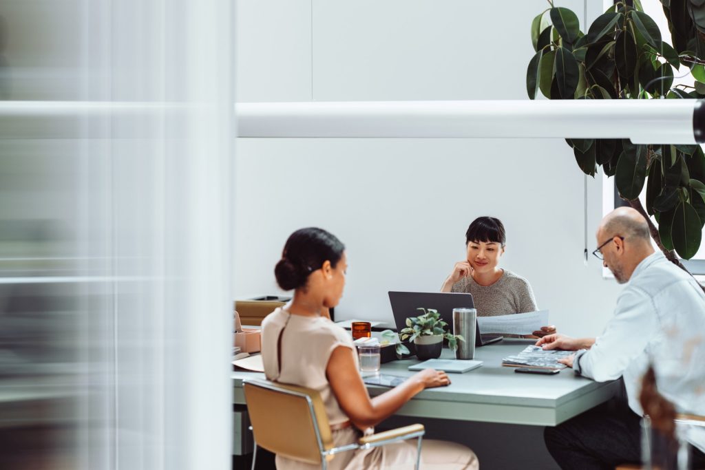 Professional business team collaborating and working on laptops in a modern office environment.