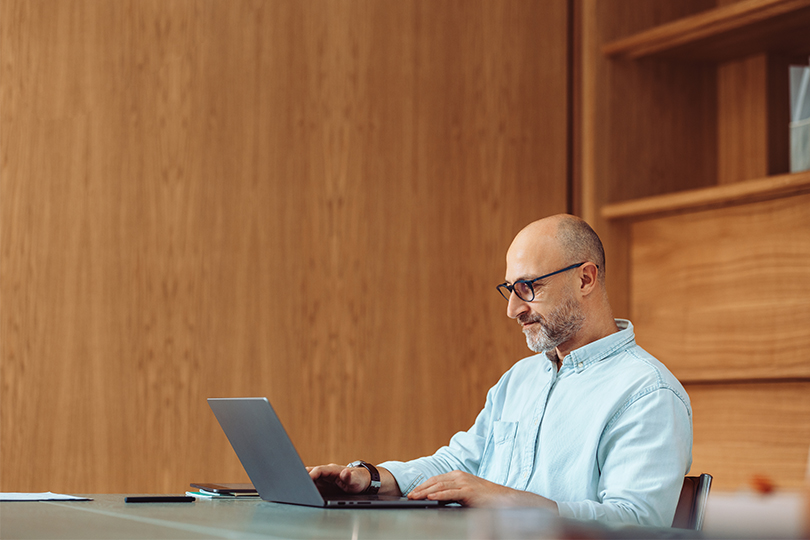 A businessman is focused on working on his laptop in a modern, stylish office environment.