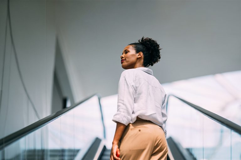A confident woman ascends a contemporary staircase, exuding elegance and grace.