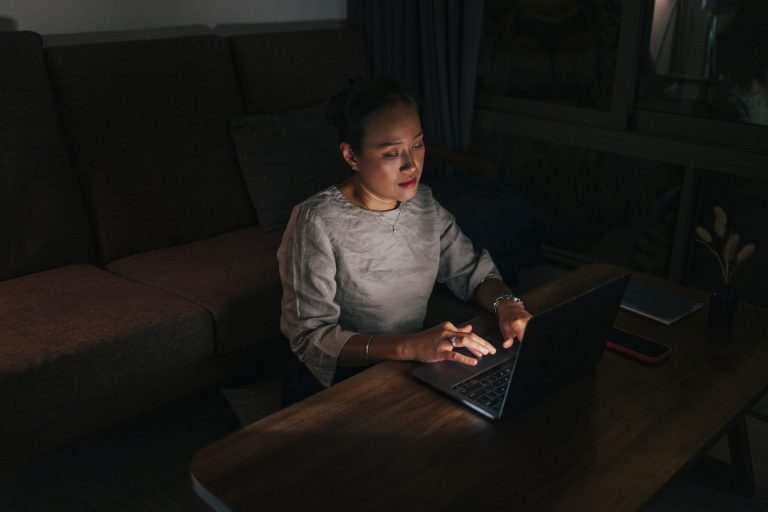 一位女性坐在家中，若有所思地看著筆記本電腦螢幕，象徵對網路財務要求保持謹慎態度。