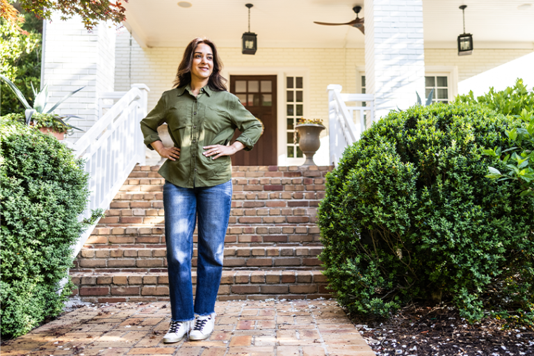 A woman standing in front of the entrance of her new home