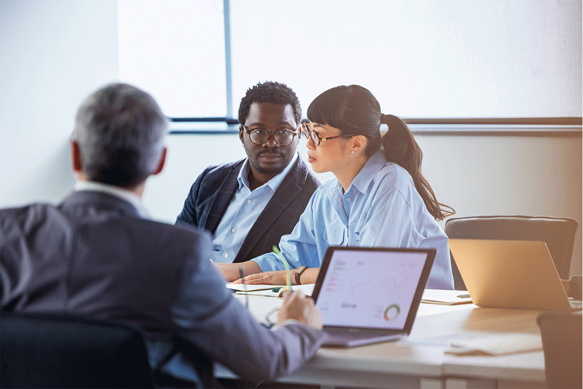 A diverse group of professionals discuss data and ideas around a conference table in a modern office